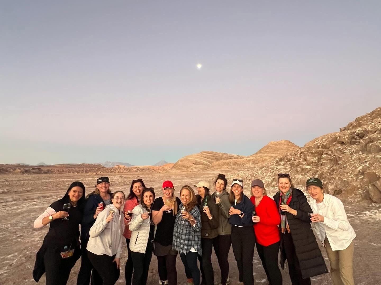 Chrissy's travel group raising a glass at dusk in the Atacama Desert, Chile, with the moon overhead