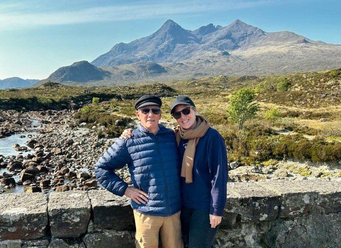 Jane and her dad in the Scottish Highlands, with mountains behind them