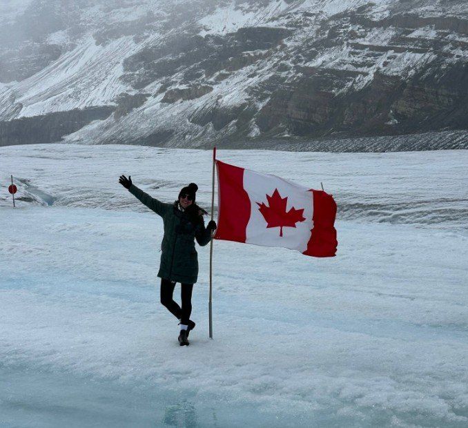 Rachael on a glacier beside a Canadian flag