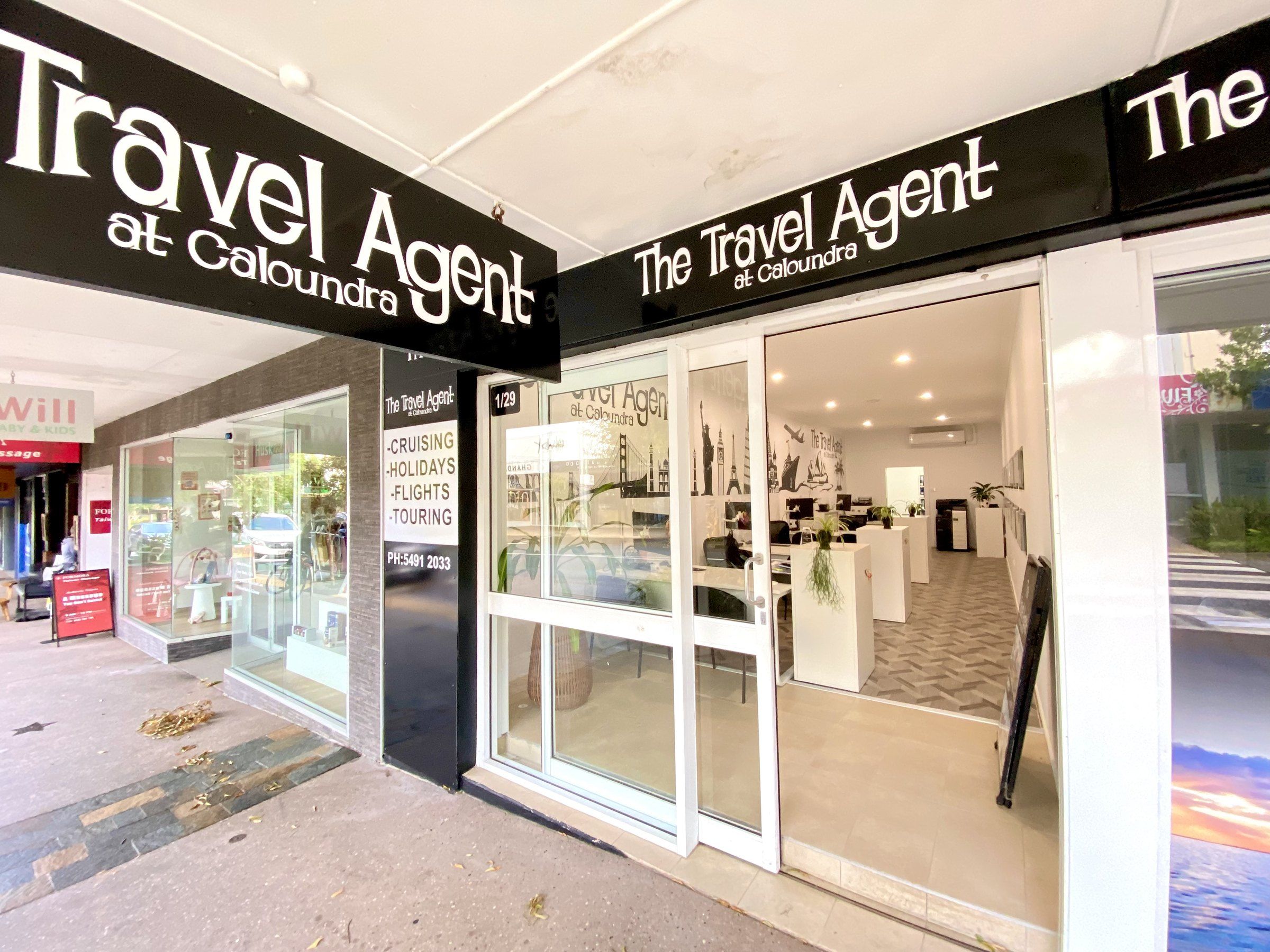 The Travel Agent at Caloundra shopfront on Bulcock Street, with the black signage and the office inside